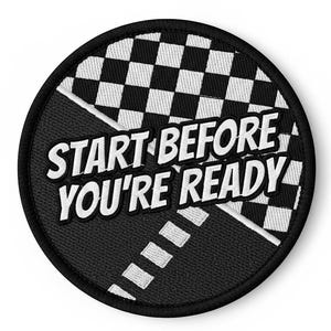 Puede incluir: Un parche bordado circular en blanco y negro con el texto "START BEFORE YOU'RE READY". El parche presenta un diseño de bandera a cuadros y una carretera con líneas discontinuas.