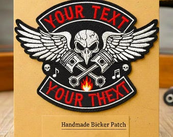 May include: Black and white embroidered biker patch with a skull, pistons, and wings design. The patch has the text "YOUR TEXT" in red and includes the text "Handmade Bicker Patch". The patch is displayed on a brown card.