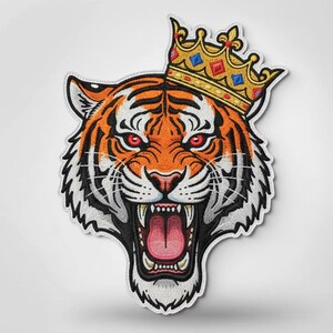 May include: Embroidered patch featuring a tiger's head wearing a gold crown with blue and red accents. The tiger has orange and black stripes, red eyes, and an open mouth. The patch has a white border.