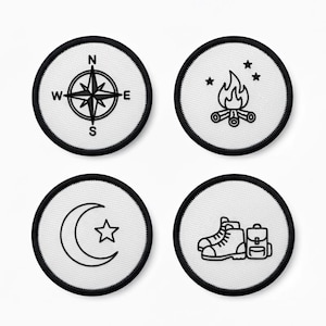 以下が含まれることがあります： 黒いステッチの縁取りが付いた4つの丸いパッチ。パッチには、コンパス、星のあるキャンプファイヤー、三日月と星、バックパック付きのハイキングブーツなど、キャンプとアウトドアをテーマにしたデザインが施されています。