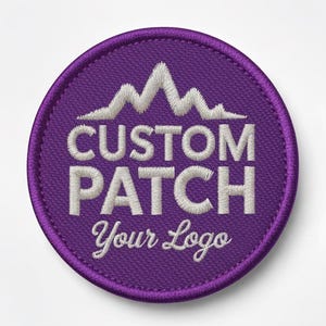 Op de afbeelding: Een ronde, paarse geborduurde patch met de woorden "CUSTOM PATCH" en "Your Logo" in het wit. Een wit bergketenontwerp staat boven de tekst. De patch heeft een paarse rand.