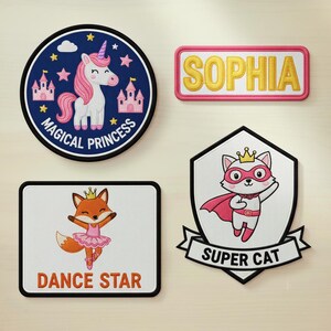 May include: Four embroidered patches with cartoon designs. A round patch features a unicorn with pink mane and tail, castles, and the text "MAGICAL PRINCESS". A rectangular patch says "SOPHIA". Another patch shows a fox in a tutu with "DANCE STAR". A shield-shaped patch says "SUPER CAT".