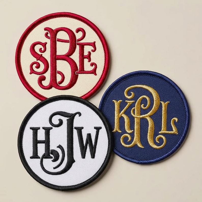 Pu&ograve; includere: Tre toppe ricamate circolari con lettere monogrammate. Una toppa ha uno sfondo color crema con lettere SBE rosse e un bordo rosso. Un'altra &egrave; bianca con lettere HJW nere e un bordo nero. La terza &egrave; blu navy con lettere KRL dorate.