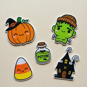 Może przedstawiać: Zestaw pięciu haftowanych naszywek o tematyce Halloween. Zawiera uśmiechniętą pomarańczową dynię w kapeluszu czarownicy, zielonego potwora Frankensteina, cukierka kukurydzianego, butelkę z miksturą i nawiedzony dom.