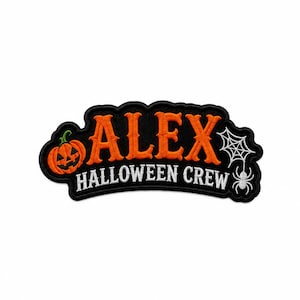 Może przedstawiać: Czarna haftowana naszywka z pomarańczowym napisem ALEX nad białym napisem HALLOWEEN CREW. Wzór zawiera pomarańczową dynię po lewej stronie oraz białą pajęczynę z wiszącym białym pająkiem po prawej stronie.