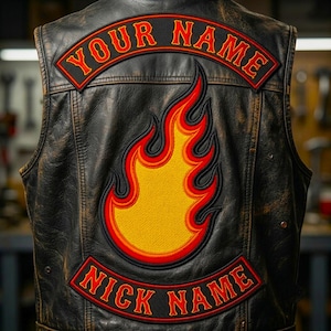 Puede incluir: Un chaleco de cuero negro desgastado con un gran parche bordado de una llama en amarillo, naranja y rojo. El chaleco incluye dos parches negros curvos con bordes rojos y texto rojo que dice "YOUR NAME" arriba y "NICK NAME" abajo.