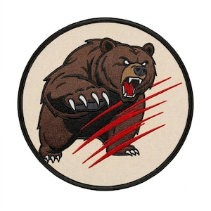 Pode incluir: Um emblema bordado circular apresentando um urso pardo com expressão agressiva, dentes à mostra e língua vermelha. O urso é retratado com garras brancas e sobreposto por quatro marcas de garras vermelhas diagonais em um fundo creme.