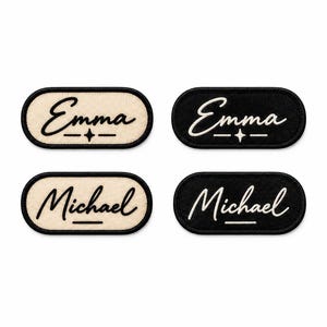 Peut inclure: Quatre écussons brodés de forme ovale avec des bordures noires. Deux écussons portent le prénom Emma et deux portent le prénom Michael en écriture cursive. Les prénoms sont centrés au-dessus d'une petite étoile et d'une ligne horizontale.