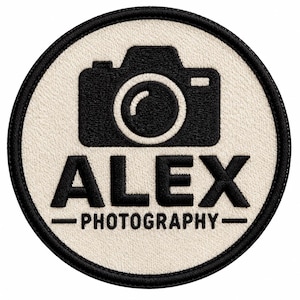 May include: A circular embroidered patch with a cream-coloured background and a black stitched border. The design features a black camera icon above the text ALEX in a bold font, with the word PHOTOGRAPHY centred below it in a smaller font.
