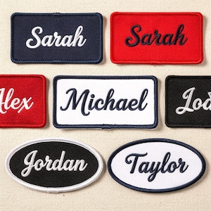 Pode incluir: Variedade de patches bordados com nomes em várias formas e cores. Patches retangulares em azul marinho, vermelho, preto e branco apresentam nomes como "Sarah" e "Michael" em escrita cursiva contrastante. Patches ovais com nomes como "Jordan" e "Taylor" também estão incluídos.