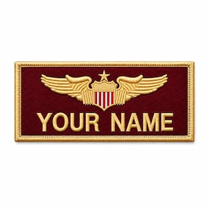 Puede incluir: Un parche rectangular bordado con fondo granate oscuro y borde dorado. Sobre el texto "YOUR NAME" hay un emblema dorado bordado que muestra un escudo con rayas verticales rojas y blancas, rematado por una estrella y un par de alas.