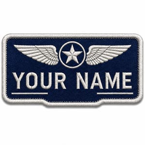 Könnte beinhalten: Ein rechteckiger, dunkelblauer Stickaufnäher mit weißem Rand. Das Design zeigt einen zentralen weißen Stern in einem Kreis, flankiert von zwei weißen Flügeln. Unter dem Emblem ist der Text YOUR NAME in weißen Großbuchstaben gestickt.