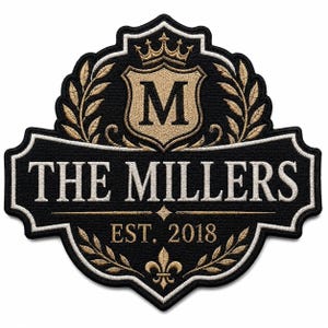 May include: A black embroidered patch featuring a gold shield with the letter M, a crown, and wheat stalks. The text reads THE MILLERS and EST. 2018 in white and gold thread. A gold fleur-de-lis is at the bottom, all enclosed in a decorative border.