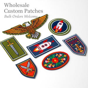 Op de afbeelding: Geborduurde patches met diverse ontwerpen, waaronder een adelaar, raket, zwaard en bloemmotieven. De patches zijn in verschillende vormen en kleuren, met de tekst "Wholesale Custom Patches Bulk Orders Welcome".