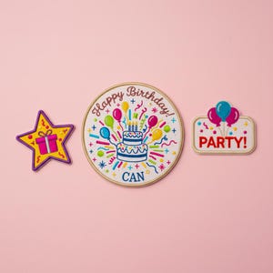 Puede incluir: Tres parches bordados sobre fondo rosa. Una estrella amarilla con un regalo morado, un parche redondo con una tarta de cumpleaños y el texto "Happy Birthday! CAN", y un parche rectangular con globos y la palabra "PARTY!"
