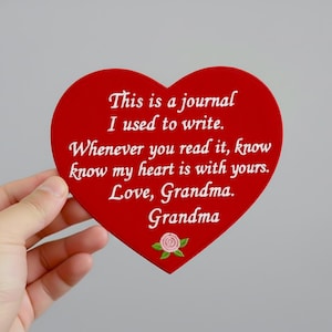 May include: A red heart-shaped plaque with white text that reads "This is a journal I used to write. Whenever you read it, know my heart is with yours. Love, Grandma. Grandma." A small embroidered rose is at the bottom.