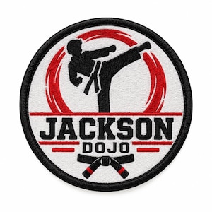 Könnte beinhalten: Ein kreisförmiger bestickter Aufnäher mit der schwarzen Silhouette eines Kampfsportlers, der einen hohen Tritt vor einem roten, kreisförmigen Pinselstrich-Hintergrund ausführt. Der Text JACKSON DOJO ist schwarz zentriert, mit einem schwarzen Gürtel.
