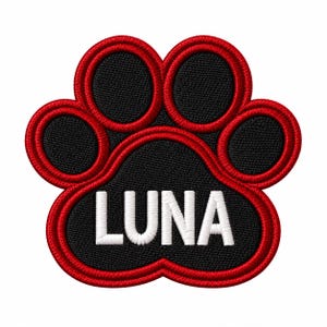 May include: An embroidered paw print patch featuring a black center and toe pads outlined in vibrant red thread. The name LUNA is stitched in bold white capital letters across the central pad of the paw, creating a clear contrast against the black background.