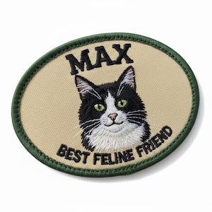 May include: Embroidered oval patch with a black and white cat and green eyes. The patch says "MAX BEST FELINE FRIEND" in black text, with a green border on a beige background.