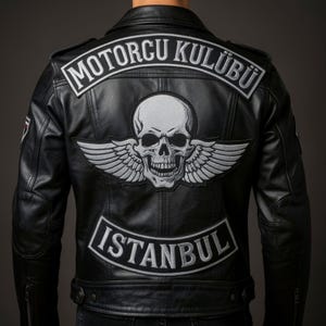 Könnte beinhalten: Eine schwarze Lederjacke mit großen gestickten Aufnähern auf der Rückseite. Der obere Aufnäher zeigt den weißen Schriftzug MOTORCU KULÜBÜ, der mittlere einen Totenkopf mit Flügeln und der untere den weißen Schriftzug ISTANBUL.