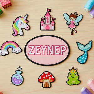 Puede incluir: Una colección de parches bordados coloridos con un unicornio, un castillo, un hada, un arcoíris, una cola de sirena, una botella de poción, una seta, una rana y un parche ovalado rosa con el nombre ZEYNEP en letras blancas.