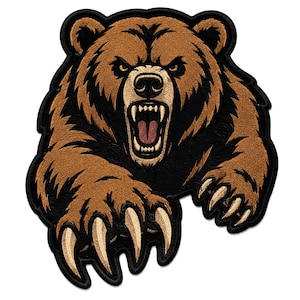 Pode incluir: Um emblema de urso pardo com uma expressão de rosnado, dentes à mostra e garras estendidas. O design utiliza fios castanhos, pretos e creme para criar uma aparência detalhada e texturizada com uma borda preta espessa ao redor da forma.