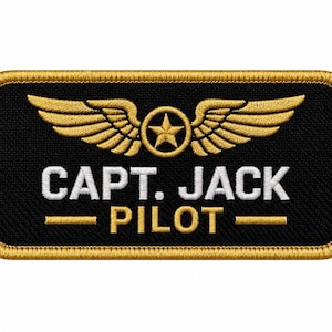 Könnte beinhalten: Ein rechteckiger bestickter Aufnäher mit schwarzem Hintergrund und goldenem Rand. Er zeigt ein goldenes Flügel-Emblem mit einem Stern in der Mitte sowie den weißen Schriftzug "CAPT. JACK" über dem goldenen Wort "PILOT", getrennt durch zwei goldene Linien.