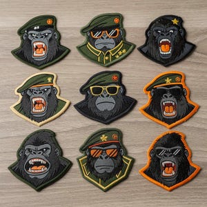 Può includere: Nove toppe ricamate raffiguranti un gorilla con la bocca aperta, che indossa un berretto e occhiali da sole. Le toppe presentano una varietà di combinazioni di colori, tra cui verde, nero e arancione. Il volto del gorilla è dettagliato con pelliccia grigia e denti bianchi.