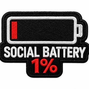 Op de afbeelding: Een geborduurde patch met een zwart batterijpictogram met een witte rand en een enkele rode balk die een laag vermogen aangeeft. Onder de batterij staat de tekst SOCIAL BATTERY in witte hoofdletters, gevolgd door een groot rood 1%-symbool.
