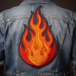 May include: A denim jacket with a large, embroidered flame patch on the back. The patch features a black outline with vibrant colors of red, orange, and yellow, creating a fiery design. The jacket is a classic blue wash.