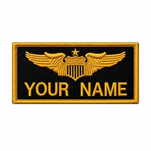May include: A rectangular black embroidered patch with a gold border. The design features a gold embroidered emblem of wings flanking a shield topped with a star. Below the emblem, the text YOUR NAME is embroidered in gold capital letters.