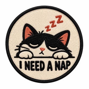 May include: A circular embroidered patch featuring a black and white cat with closed eyes resting its head on its paws. The cat has pink inner ears and a pink nose. Above the cat are red ZZZ letters, and below is the text I NEED A NAP in black.