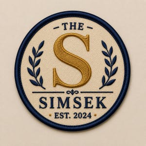 May include: A circular embroidered patch with a cream-coloured background and a dark navy blue border. It features a large gold letter S in the centre, flanked by two navy blue laurel branches. Below, the text reads THE SIMSEK EST. 2024 in navy blue.