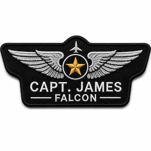 May include: A black embroidered patch featuring a gold star centred within a circle, flanked by silver wings. Above the circle is a small white aeroplane icon. The text reads CAPT. JAMES FALCON in white capital letters with a horizontal line.