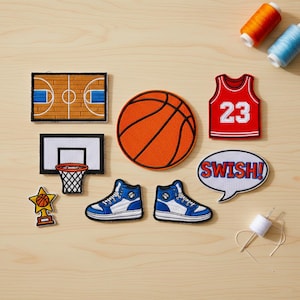 Puede incluir: Un conjunto de parches con temática de baloncesto, que incluyen una cancha de baloncesto, un balón, una camiseta con el número 23, un aro de baloncesto y zapatillas altas. Los parches son de varios colores, como naranja, rojo, azul y blanco.