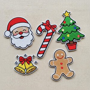 May include: A selection of embroidered Christmas patches. Features Santa Claus, a candy cane with a red bow, a Christmas tree with baubles, golden bells with a red bow, and a gingerbread man.