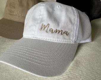 May include: White, brown, and black baseball caps with mesh panels. The white cap has the word "Mama" embroidered on the front in gold thread.