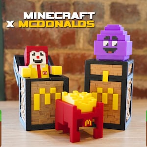 May include: Minecraft and McDonald's collaboration featuring a purple character in a chest, a red and yellow character in a chest, and a red and yellow McDonald's themed block.
