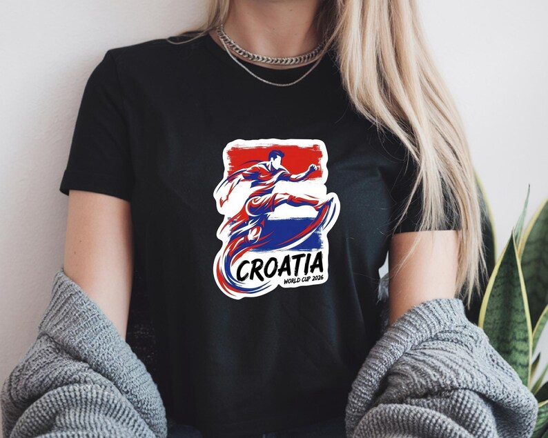 A person wearing a black t-shirt with a graphic design featuring a figure in a red, white, and blue outfit, along with the text "Croatia" and "World Cup of Croatia".