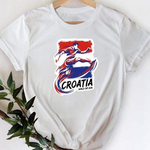 A white t-shirt with a graphic design featuring a person in a fighting stance, along with the text "Crotia" and "World Cup of 2018" printed on it.