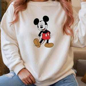 A person wearing a white sweatshirt with a Mickey Mouse graphic printed on it.