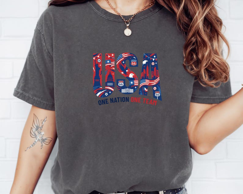 A person wearing a gray t-shirt with a graphic design featuring various symbols and text related to the United States.