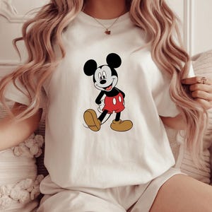 A woman wearing a white t-shirt with a Mickey Mouse graphic on it.