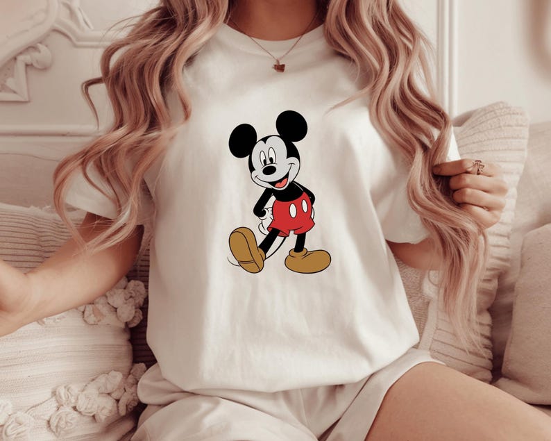 A woman wearing a white t-shirt with a Mickey Mouse graphic on it.