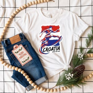 a white t-shirt with a graphic of a surfer, a pair of blue jeans, and a Christmas ornament.