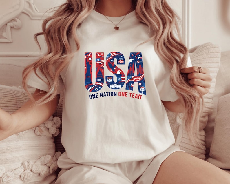 A woman wearing a white t-shirt with the text "USA" and "ONE NATION ONE TEAM" printed on it.