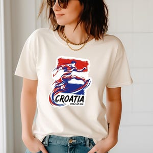 A woman wearing a white t-shirt with a graphic design of a person in a fighting stance and the text "CROATIA" printed on it.
