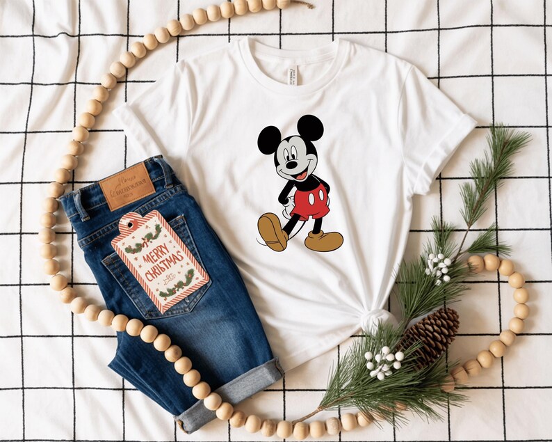 a white t-shirt with a Mickey Mouse graphic, a pair of blue jeans, and some Christmas decorations, including a string of beads and pine cones.