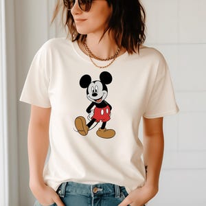A woman wearing a white t-shirt with a Mickey Mouse graphic and sunglasses.