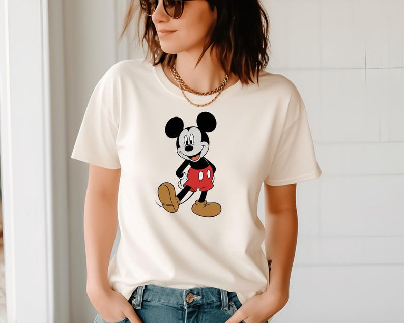A woman wearing a white t-shirt with a Mickey Mouse graphic and sunglasses.